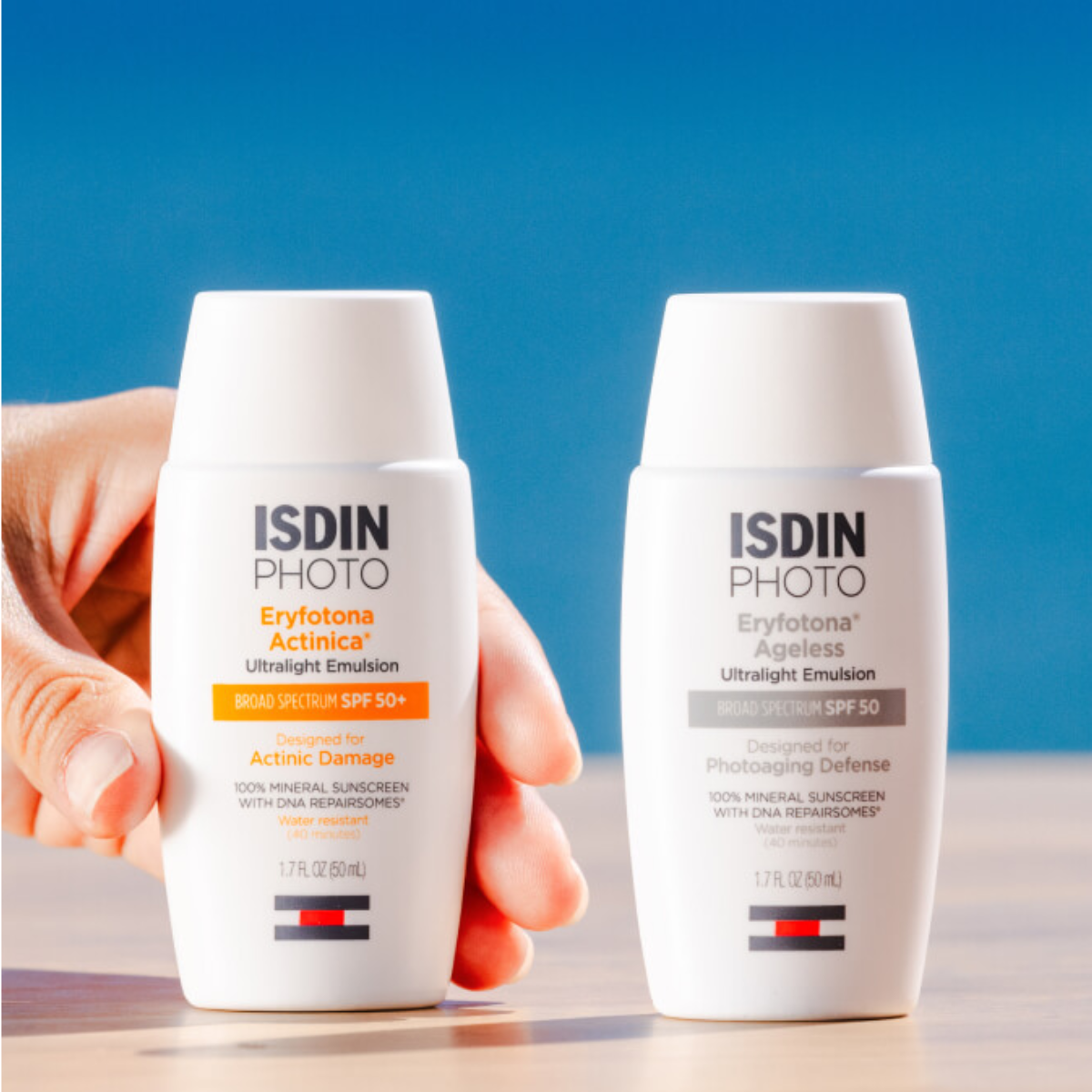 Two bottles of ISDIN Photo sunscreen on a blue background